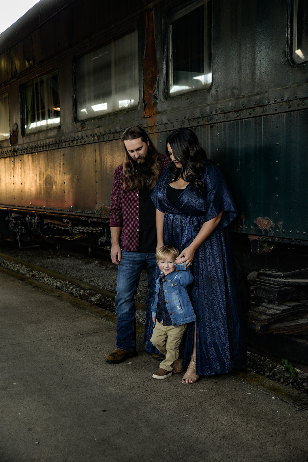 Outdoor portrait session at golden hour, family together in open field with soft warm light on their faces