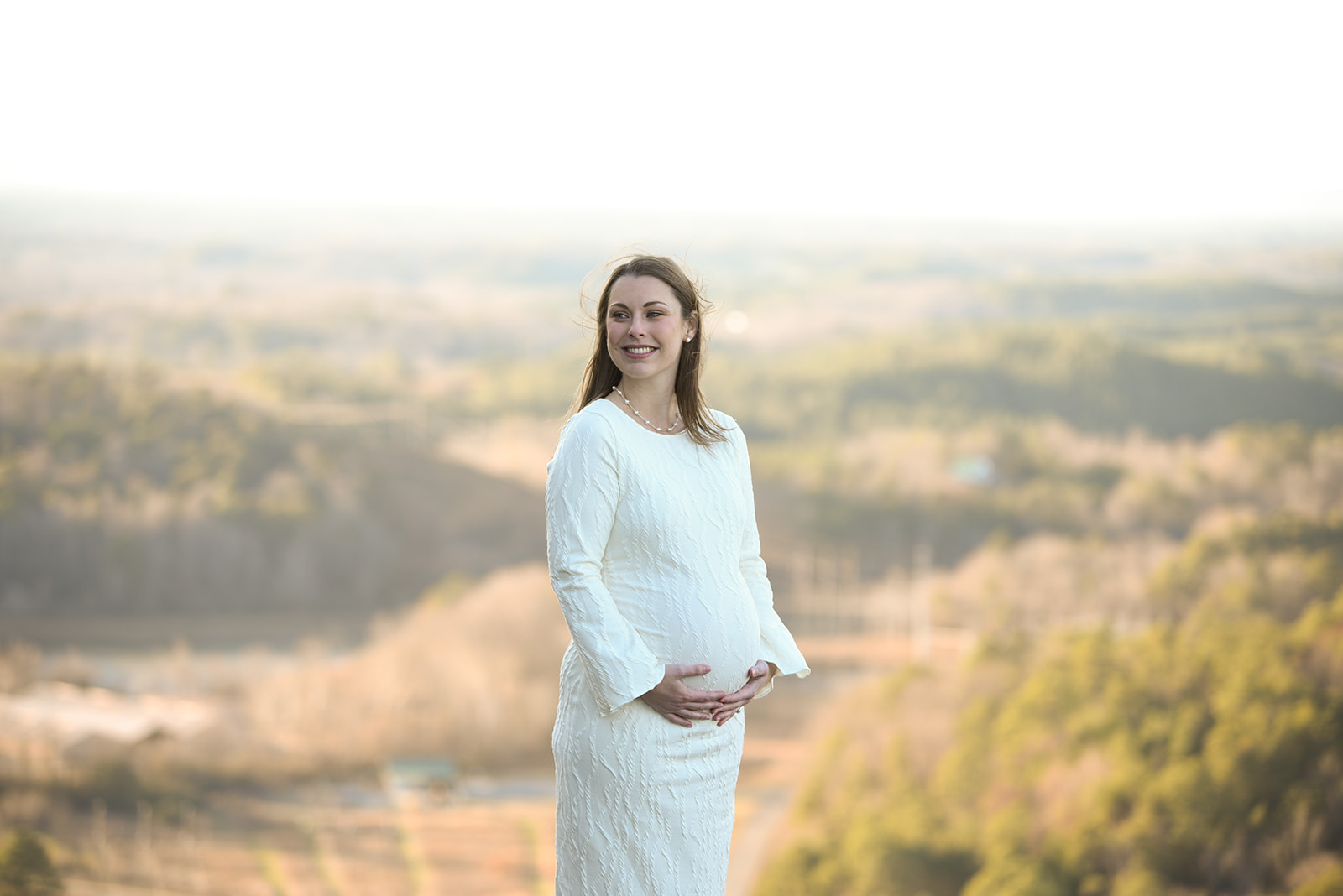 Maternity session detail — expectant mother's hands cradling belly in soft afternoon light