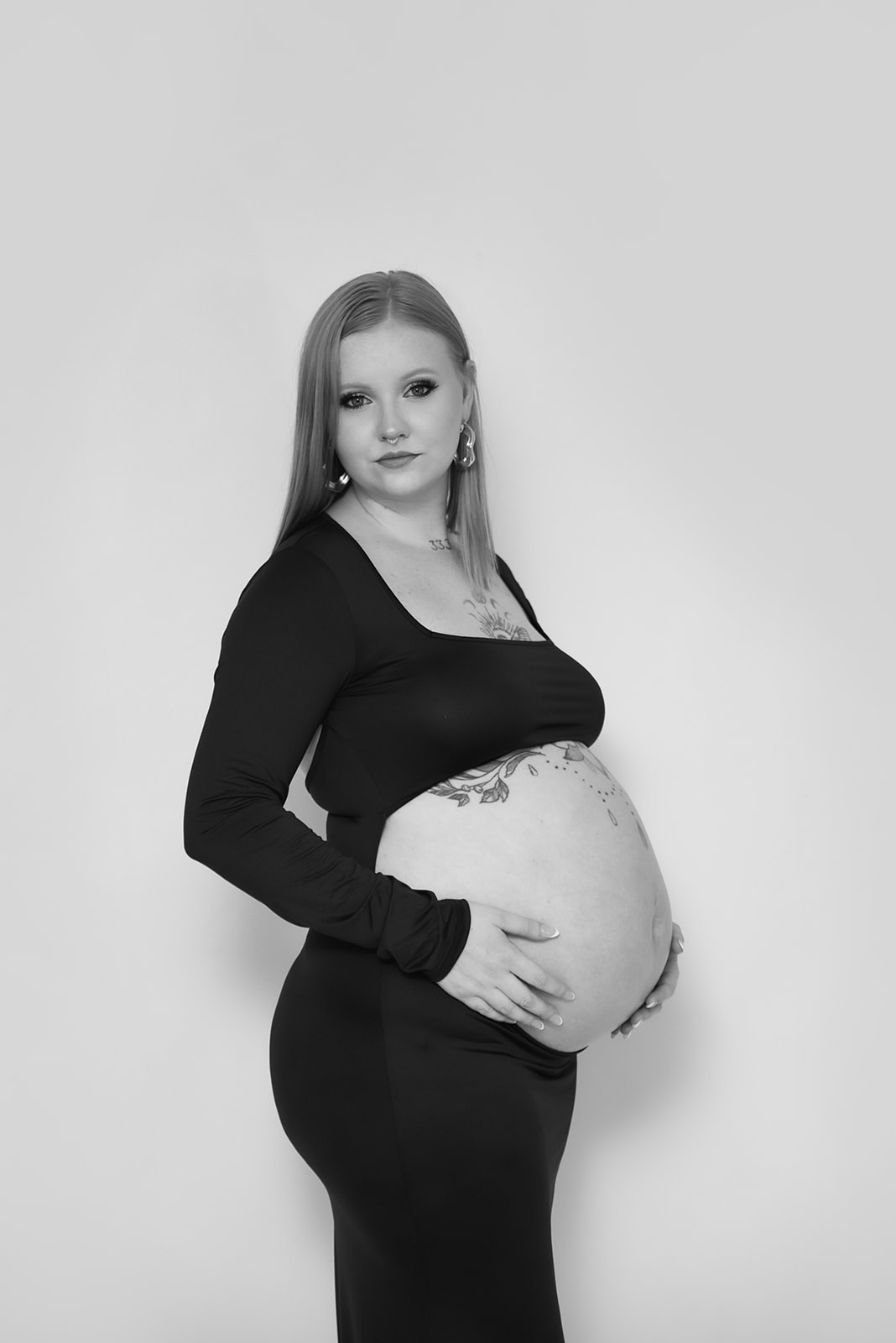 Maternity portrait of woman in flowing gown standing in tall grass, Blue Ridge foothills behind her