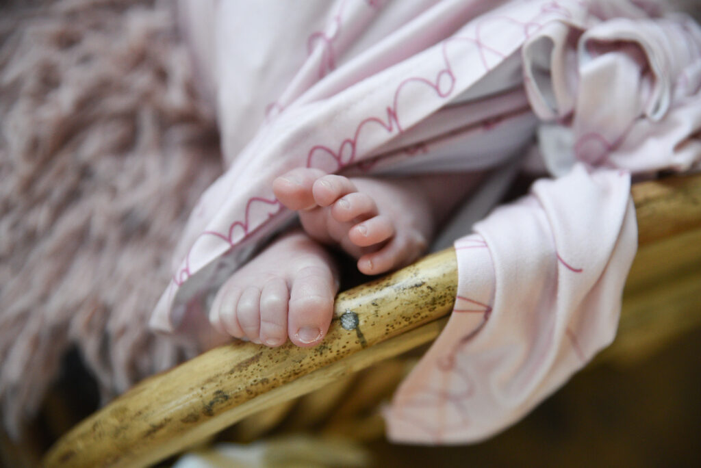 Newborn baby curled in soft wrap during natural light newborn photography session