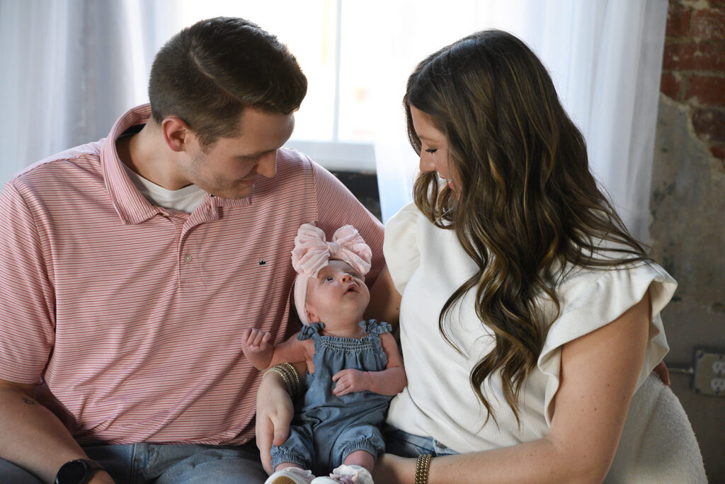 Newborn baby curled in soft wrap during natural light newborn photography session