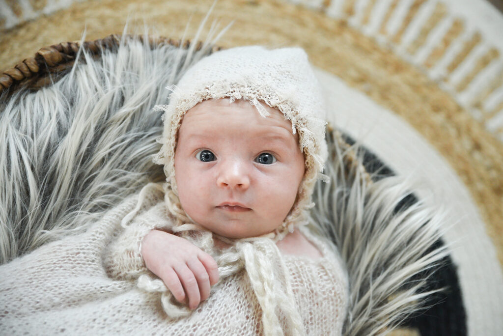 Newborn baby curled in soft wrap during natural light newborn photography session