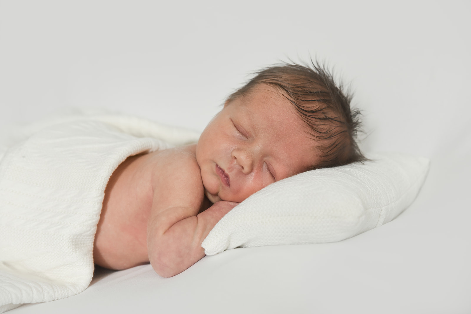 Sleeping newborn curled in soft wrap during Sugar Hill GA lifestyle photography session